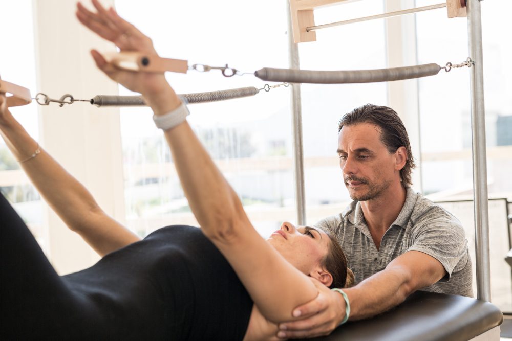 Miguel Silva, Pilates instructor assisting his client while doing the Pilates exercises