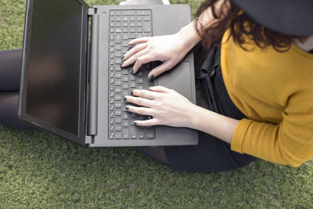 Female blogger writing on her laptop while sitting down