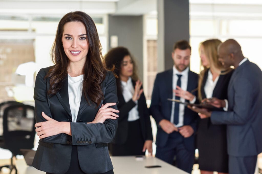 Business woman standing confidently in a crowd of her peers.