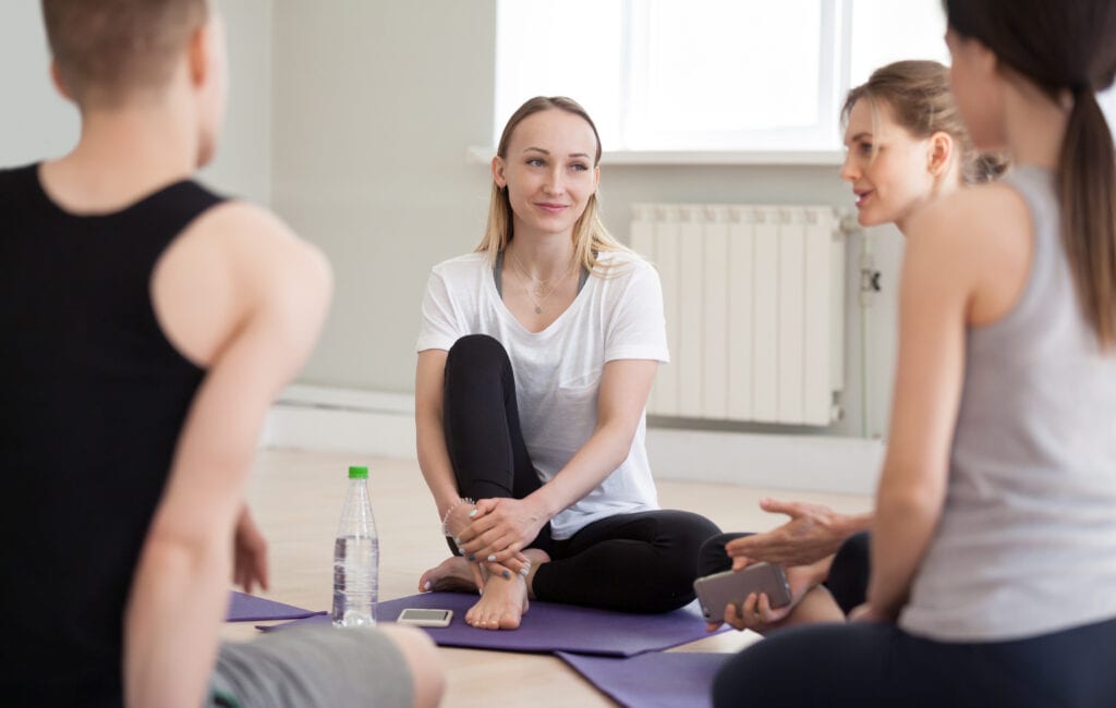 Pilates teachers sitting in mat and having conversations with her students