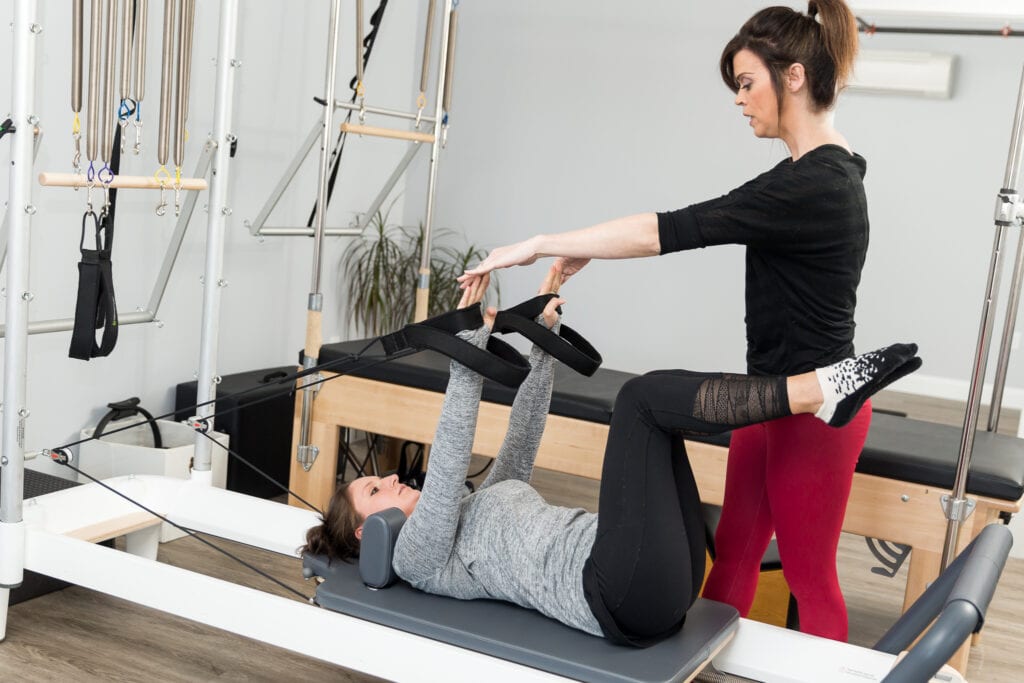 Nadine Taylor, Pilates instructor assisting her client while doing the Pilates exercises on the Reformer