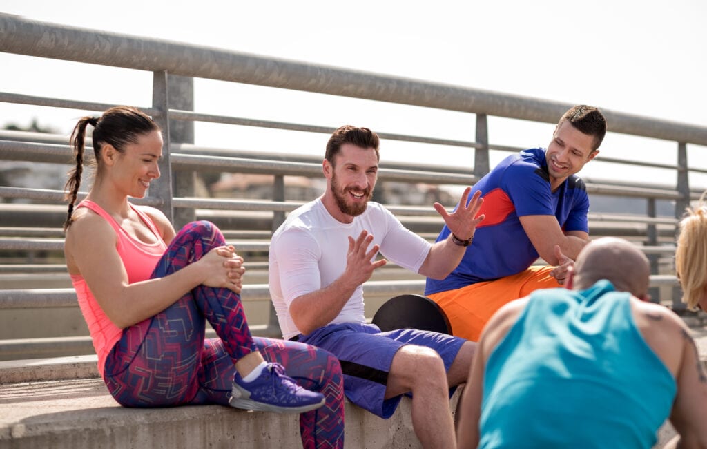 Group of athletic people sitting and talking outside.