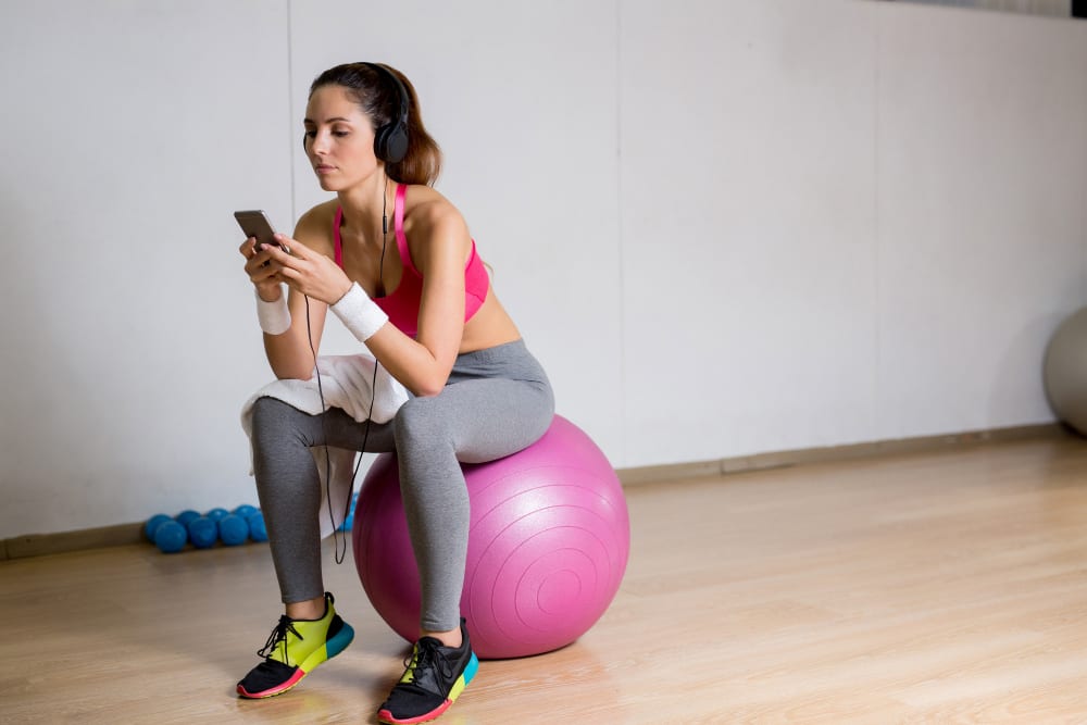 Pilates teacher watching on her phone after training on Pilates Ball