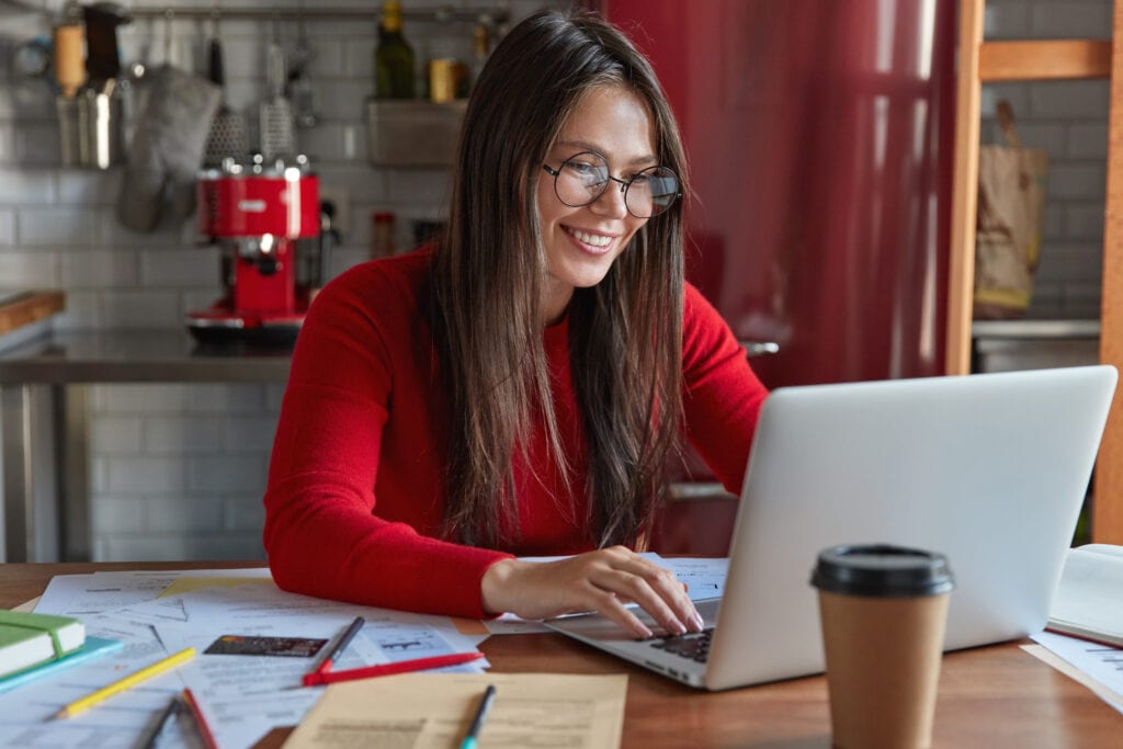 Woman working on her office while having coffee beside her laptop