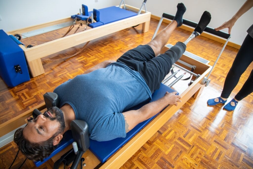 Pilates male client working out on the Pilates Reformer