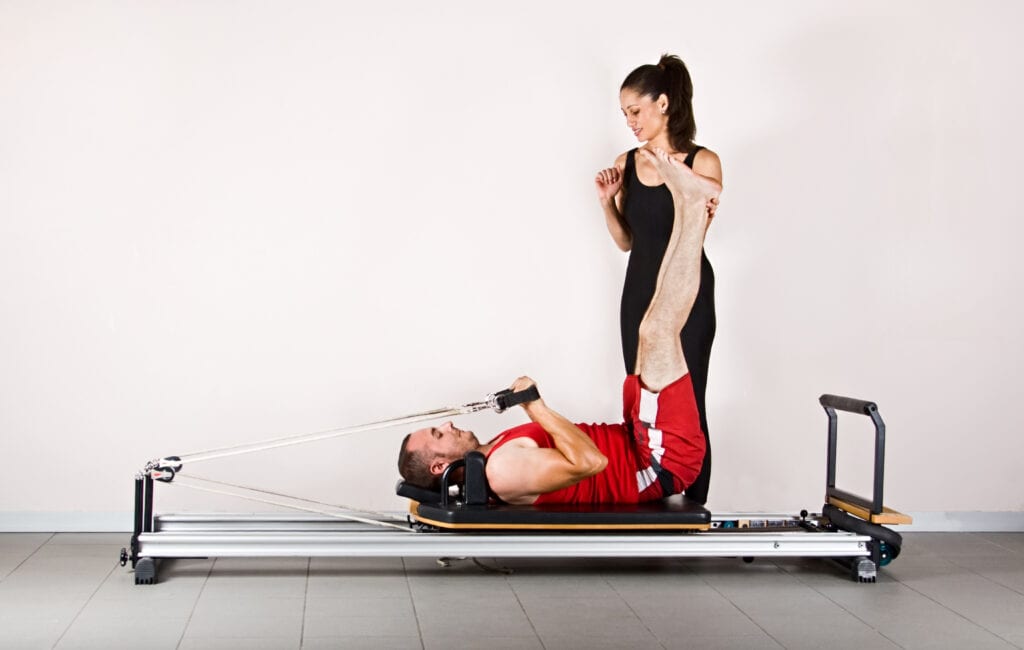 Pilates teacher assisting her client while doing the exercise on Pilates reformer