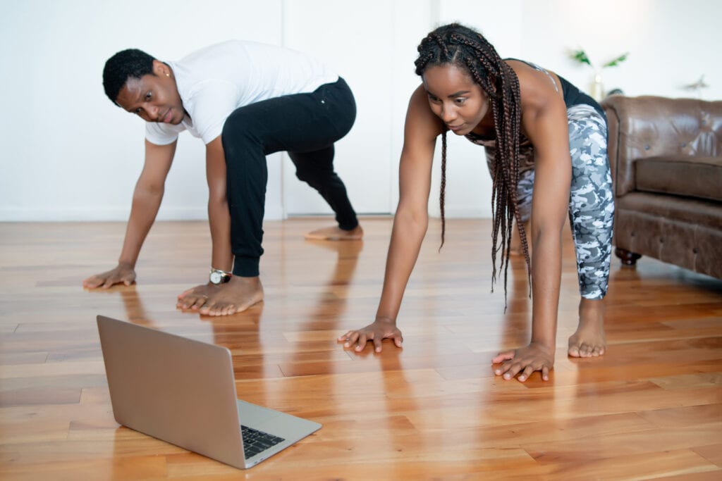 Man and woman doing exercise together while watching the Pilates video tutorial