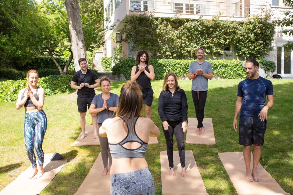 Group of people exercising on mats  on a lawn