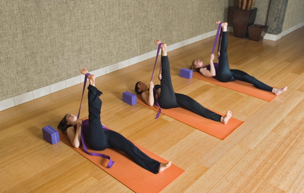 Women laying on mats exercising with therabands and blocks in studio