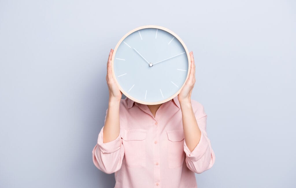 Female holding a wall clock in front of her face