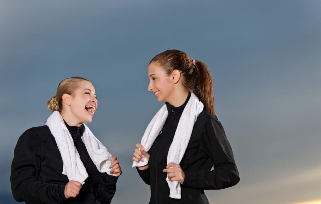 Two young women laughing with towels around their necks