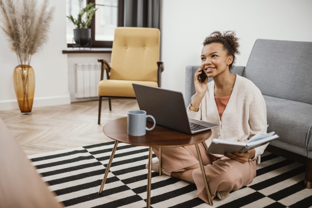 A young woman talking to her client while checking her social media account on her laptop